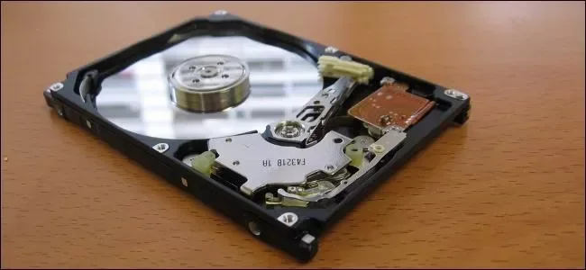 An open hard disk drive with its circular platter and read/write arm exposed.