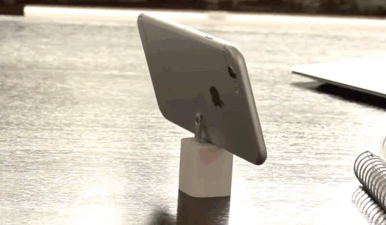 iPhone mounted upright on a small stand outdoors.